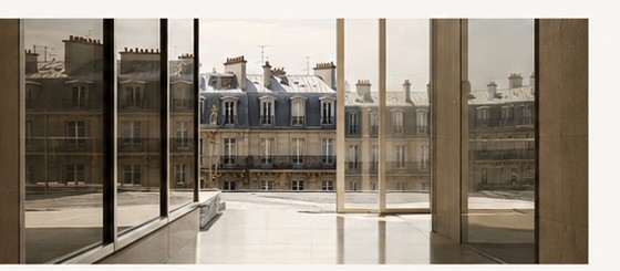 An interior looking out across limestone rooftops — context and place.